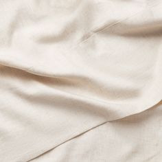 an unmade bed with white sheets and pillows