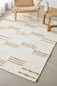 a white rug with brown lines on it in front of a chair and coffee table