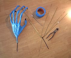 an assortment of crafting tools on a wooden table with blue plastic gloves and needles