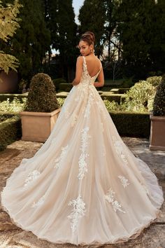 a woman in a wedding dress standing on a stone walkway with her back to the camera