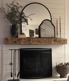 a living room with a fireplace, mirror and vase on top of the mantel