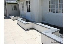 some concrete benches sitting in front of a white building with windows on the side of it