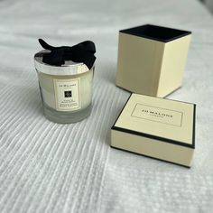 a candle sitting on top of a bed next to a box with a black bow