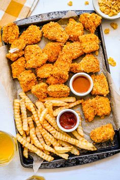 chicken nuggets and fries on a tray with ketchup, mustard, and dipping sauces