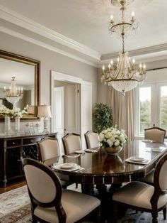 a formal dining room with chandelier and large table surrounded by chairs in front of windows