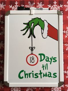 an image of a christmas sign with the grin's hand holding a bell ornament