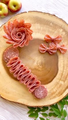 sliced meats arranged in the shape of a heart on top of a wooden plate