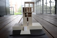 a model of a house sitting on top of a wooden floor next to a black mat