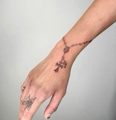 a woman's hand with a cross tattoo on the middle of her left arm