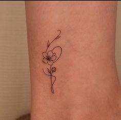 a small flower tattoo on the side of a woman's leg, with an arrow in the center