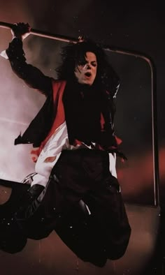 a man with black hair and makeup jumping in the air