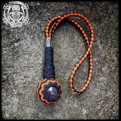 an orange and black lanyard with a metal ball on it's end is laying on the ground