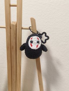 a crocheted animal keychain hanging on a wooden ladder with a white wall in the background