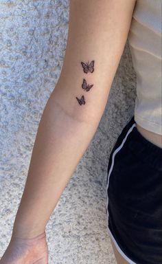 a woman's arm with three butterflies tattooed on the left side of her arm