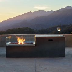 an outdoor fire pit sitting on top of a cement floor next to a glass of wine