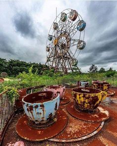 an abandoned ferris wheel sits in the middle of a park filled with rusted seats