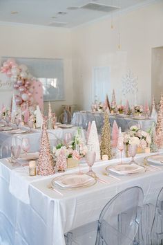 a table set up with pink and gold decorations for a winter themed party or wedding