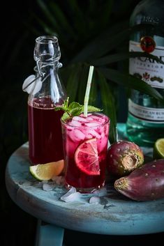 two glasses filled with different types of alcoholic drinks next to some tropical fruit and ice