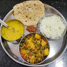 a silver plate topped with different types of food next to rice and pita bread