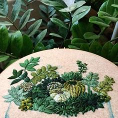 an embroidered rock with leaves and flowers on it