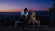 a man and woman sitting on a bench at night