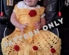 a baby sitting in a stroller wearing a crocheted dress with roses on it