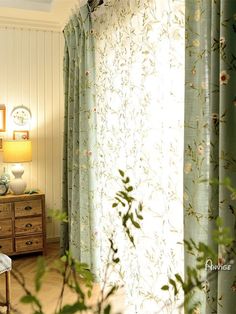 the curtains are open in the room by the dresser and table with flowers on it