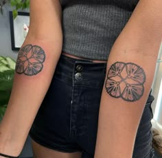 two women with matching tattoos on their arms, both holding each other's hands