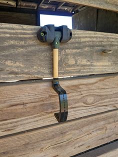 a wooden bench with a metal hook on it's side and wood planks in the background