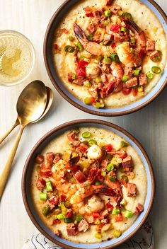 two bowls filled with shrimp and grits on top of a table next to a spoon