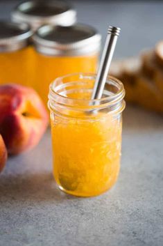 a jar filled with orange liquid next to some sliced peaches on a counter top