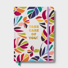 a colorful notebook with the words take care of you printed on it and leaves in gold foil