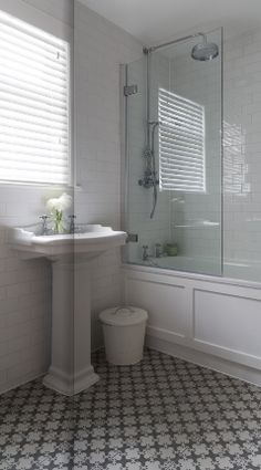 a white bathroom with black and white tile flooring on the walls, shower stall, toilet and sink