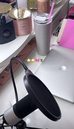 a laptop computer sitting on top of a desk next to a cup and other items