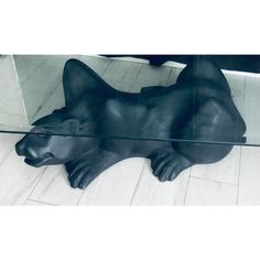 a glass table topped with a black bear statue