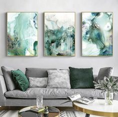 three paintings on the wall above a couch in a living room with coffee table and chairs