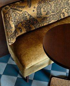 a wooden table sitting next to a brown chair on top of a blue and white checkered floor