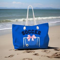 a blue soccer bag sitting on top of a sandy beach next to the ocean,