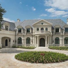 a large white house with lots of windows and bushes in front of the entrance to it