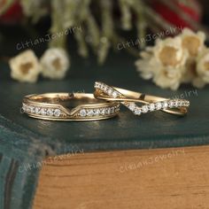 two wedding rings sitting on top of a book with flowers in the backgroun