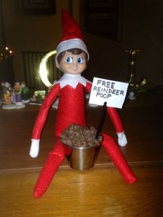 an elf is sitting on the table holding a sign