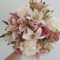 a bridal bouquet with pink and white flowers is held by someone's hand