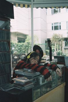 a person with headphones on sitting in front of a record store counter filled with records