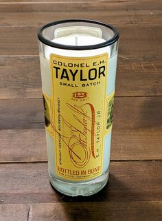 a candle that is on top of a wooden table in front of a glass bottle