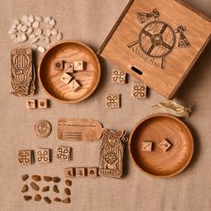 wooden stamps and dices are sitting on a table next to a box with some other items in it