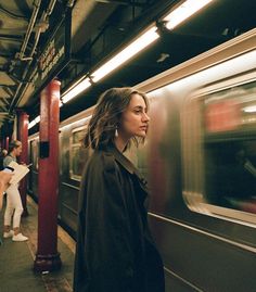 a woman is waiting on the subway platform for her train to stop and look out