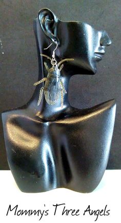 there is a black sculpture with gold earrings on it's head and the words mommy's three angels written below it