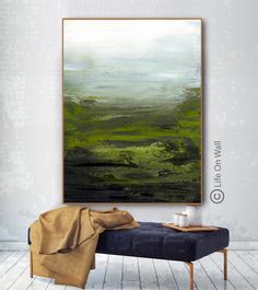 an abstract painting hangs on the wall above a bench in a room with white walls