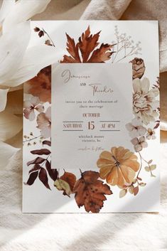 a wedding card with leaves and flowers on it