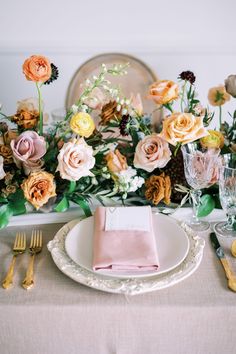 the table is set with pink napkins and gold place settings, along with flowers